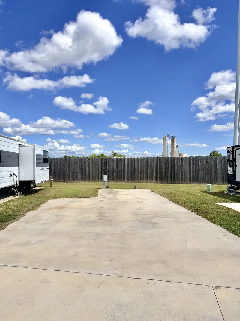 Concrete RV pad, electrical hookup, and tall privacy fence